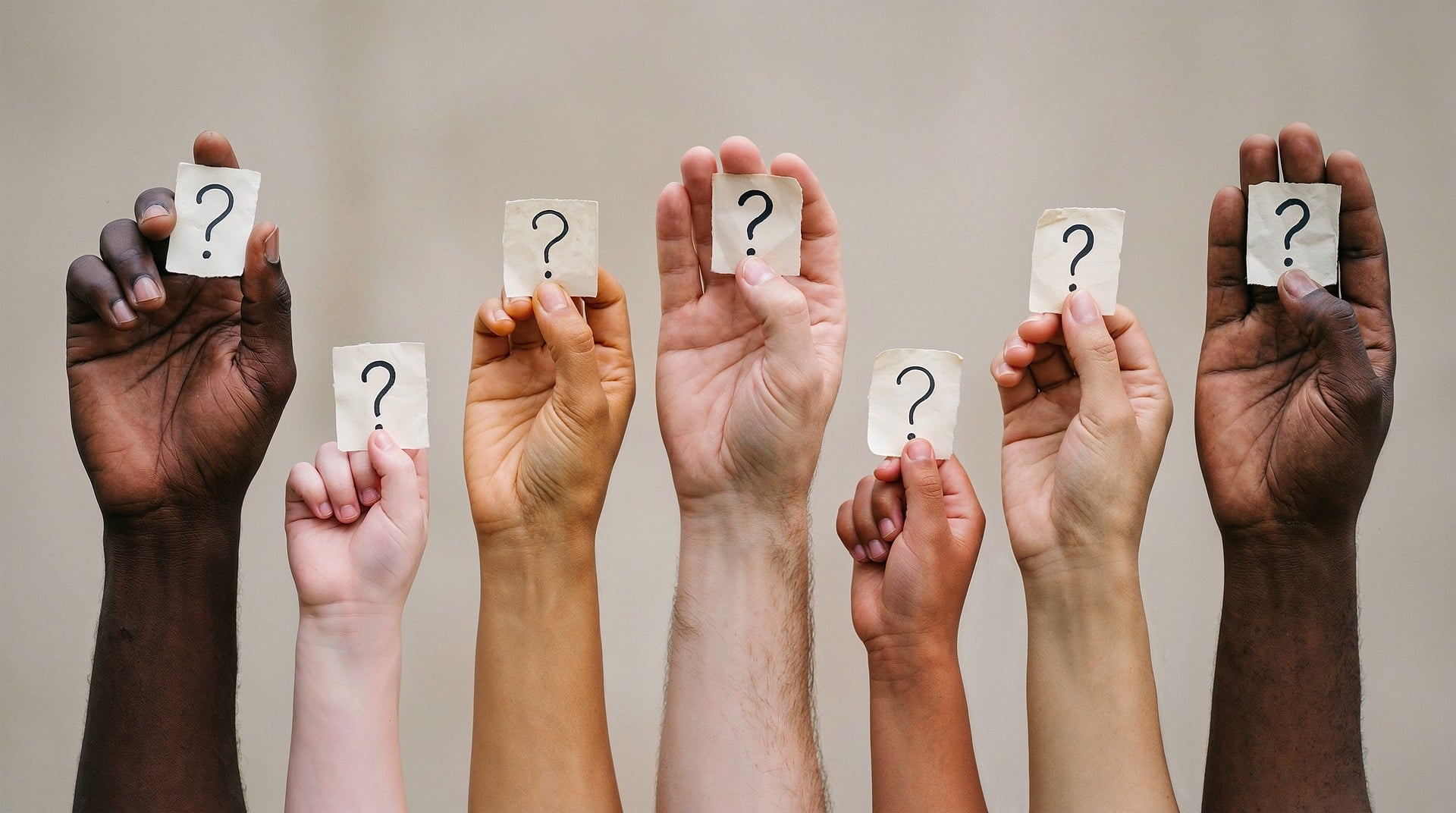 Home 4 Sei braccia e mani di diverse tonalità di pelle sono sollevate verso l'alto contro uno sfondo grigio chiaro e neutro. Ogni mano stringe tra le dita un piccolo pezzo di carta stropicciata su cui è disegnato un punto interrogativo nero.